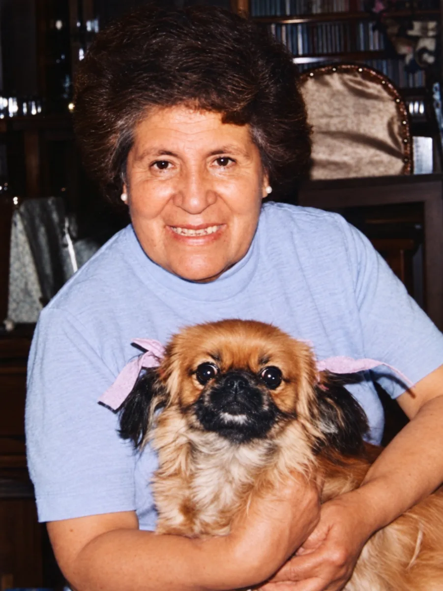 Yolanda sonriente abrazando a su perrito pequinés